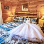 A white wedding dress laid out on a log bed.