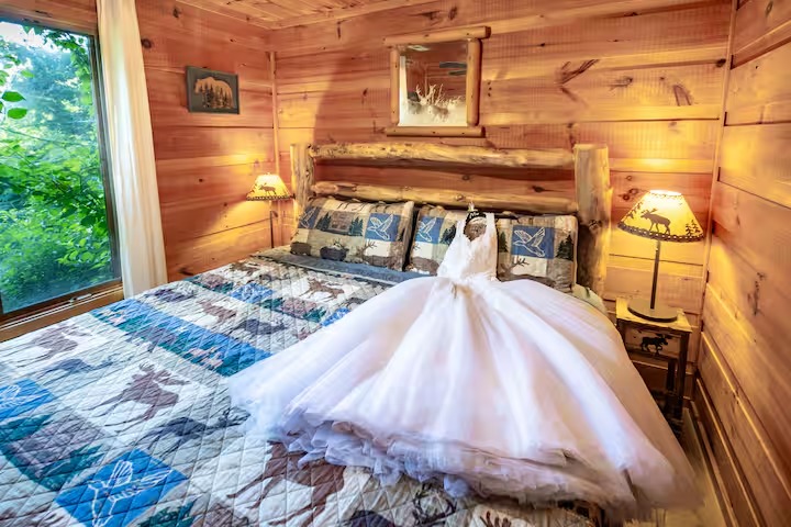 A white wedding dress laid out on a log bed.