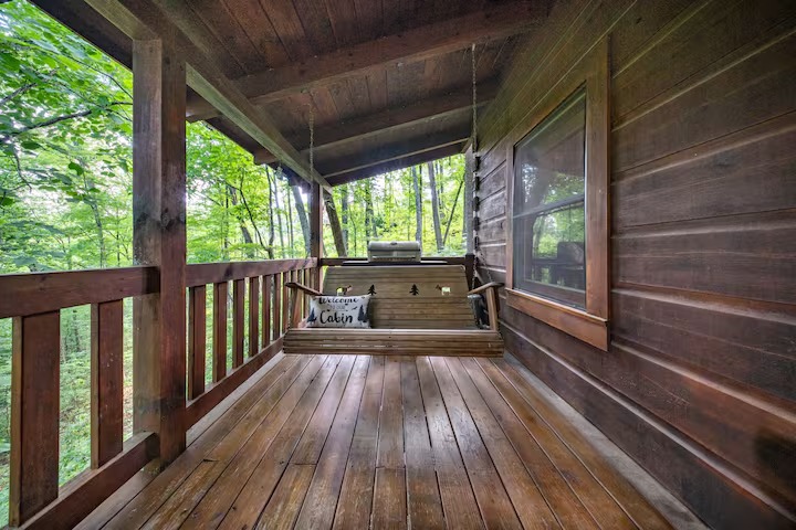 A rustic cabin bathroom featuring natural wood walls, a walk-in corner shower with glass doors, a wooden vanity cabinet, and a white toilet.