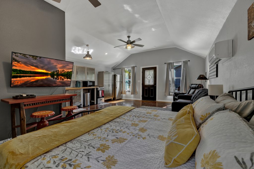 High-angle shot from the bed looking toward the kitchen and living room, highlighting the glossy stained concrete floors.