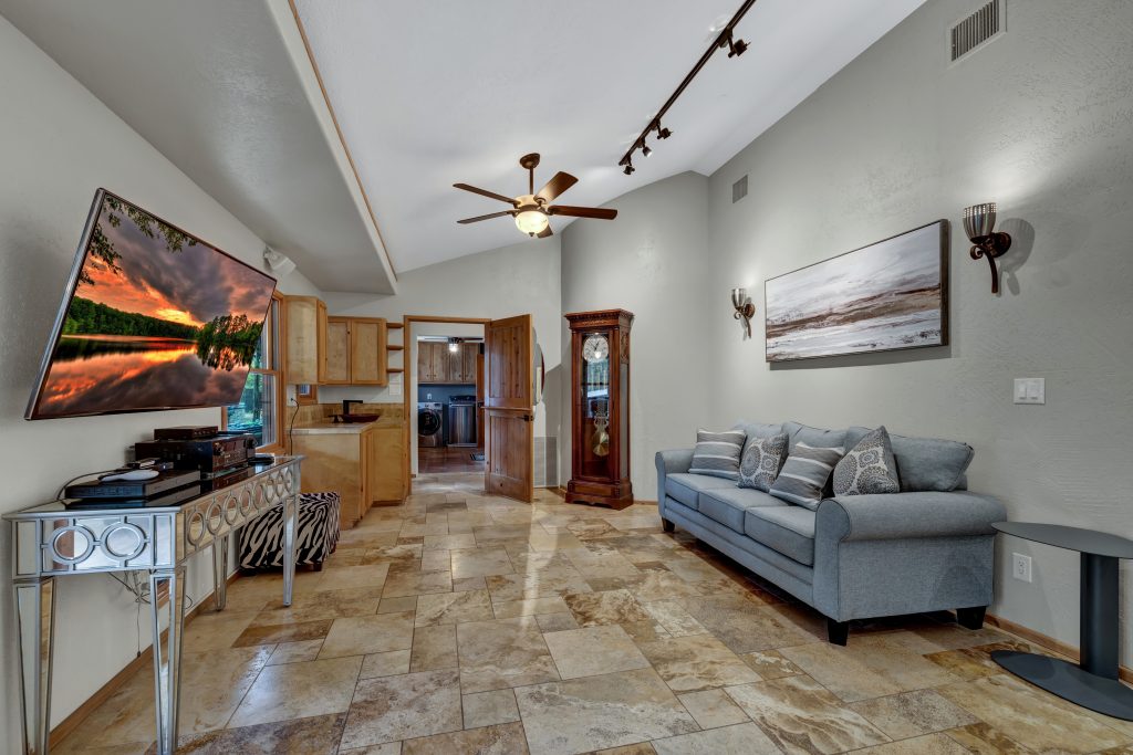 A spacious master suite featuring a vaulted ceiling, a seating area with a sofa, and an en-suite bathroom.