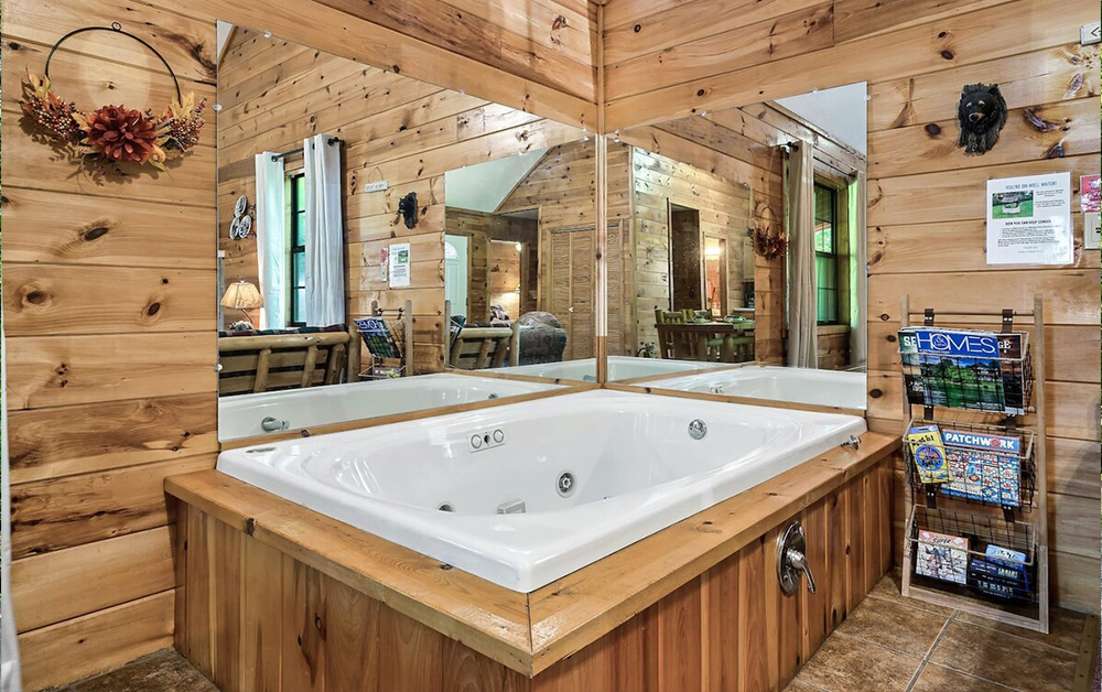 A charming wooden cabin with a green roof surrounded by trees, perfect for a Romantic Getaway With Hot Tub.