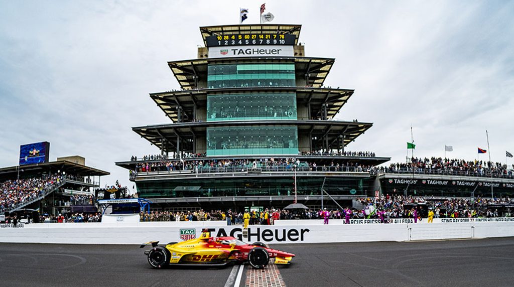 Indianapolis Motor Speedway Pagoda with IndyCar crossing Yard of Bricks, vibrant racing atmosphere near short term rentals Indianapolis.