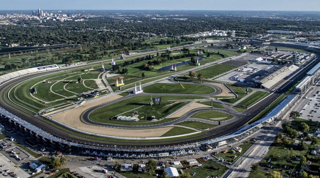 Aerial view of Indianapolis Motor Speedway oval track, grandstands, and city skyline near short term rentals Indianapolis.