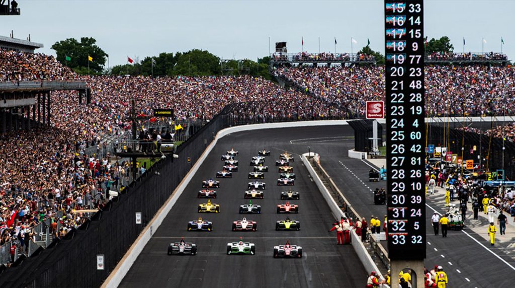 Packed grandstands and IndyCars lined up on the grid at the 2026 Indy 500 race start.