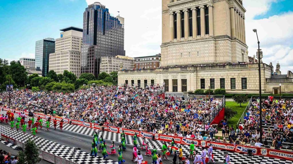 Colorful parade with grandstands and crowds celebrating the 2026 Indy 500 in downtown Indianapolis.